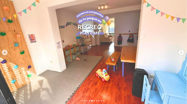 Sala interior con muro de escalada, juegos y mesa de trabajo para niños